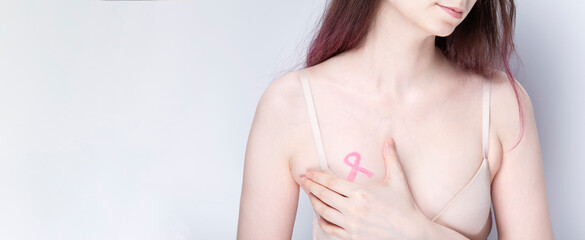 World Breast cancer day concept. Woman in bra with pink ribbon painted on her chest. October Breast Cancer Awareness month. Copy space