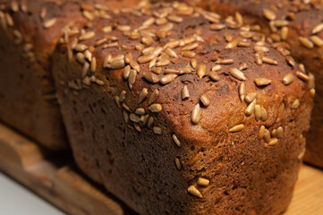 fresh brown loaves of rye bread in the form of bricks with sunflower seeds on a crust. Lie on a wooden rack