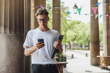 Young handsome man goes to the university and writes a message in the smartphone. A modern man does business in a smartphone.