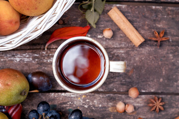 Cozy rustic still life: cup of tea, fruits, vegetables, hazelnuts and cinnamon sticks. Autumn aesthetic still life. Thanksgiving Day concept with place for text.