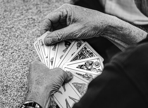 Persona mayor y jubilada jugando con una baraja de cartas espa&ntilde;olas