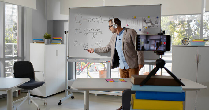 Mature math teacher recording tutorial video for students on smartphone