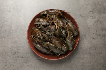 Fototapeta na wymiar Fresh raw crayfishes in bowl on grey table, top view