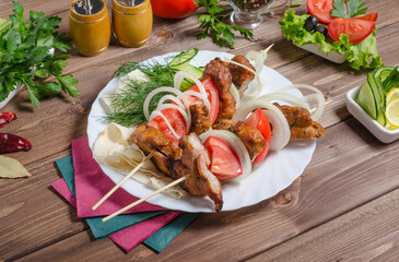 Pork shashlik with onions on a white plate close-up on a dark wooden background