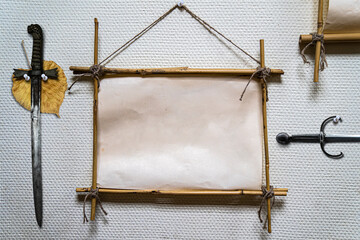 Bamboo sticks frame sign with vintage old paper. Decorated with two old daggers and autumn leaves. Stationery mockup.