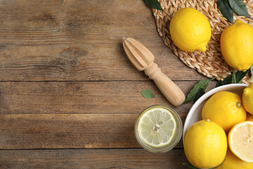 Squeezer with lemons on wooden table, flat lay. Space for text
