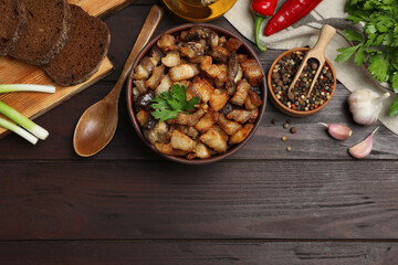 Tasty fried cracklings and different ingredients on wooden table, flat lay with space for text. Cooked pork lard