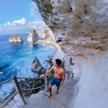 Man climbing rock staircase beside beach
