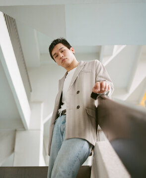 Man in gray blazer and blue denim jeans standing on staircase
