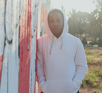 Man in hoodie standing beside wall