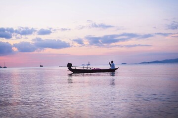 Man sitting on fishing boat on sea during sunset
