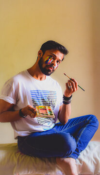 Man painting on his face sitting on bed