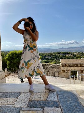 Photographer women in a white and yellow dress in Acropolis of Athens, Greece