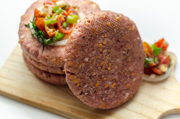 Raw beef burgers blended with caramelised red onion and tangy red Leicester cheese prepared for grilling