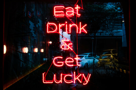 Red neon light signage that says Eat Drink & Get Lucky