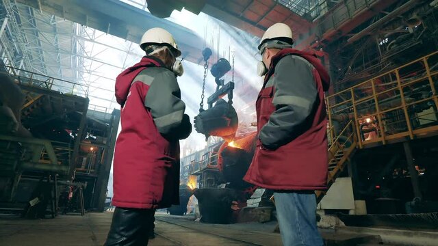 Steel mill employees are discussing metal casting
