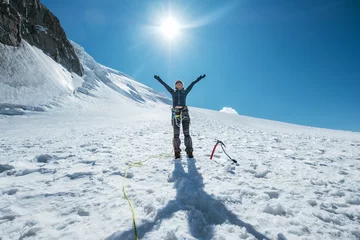 Crédence de cuisine en verre imprimé Mont Blanc La femme a levé les bras et souriant joyeusement en gravissant le sommet du Mont Blanc (Monte Bianco) vêtue de vêtements d& 39 alpinisme avec un harnais d& 39 escalade sur les pentes enneigées du Mont Blanc du Tacul.