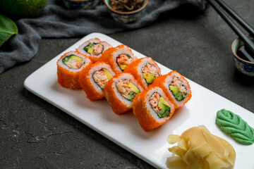 California roll with crab on white plate on dark stone table