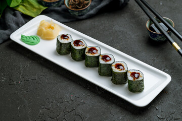 Roll unagi Maki on white plate on dark stone table