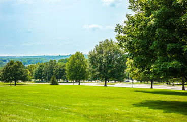 Scenic of green landscape, public outdoor park for leisure and picnic in summer. Greenery environment, lush field and trees and blue sky. Recreation and relaxation place with nature. Depth of field.