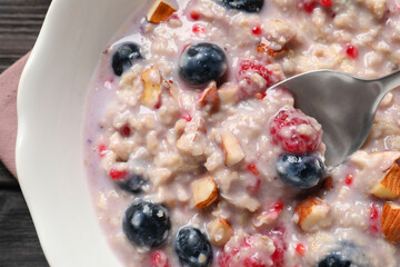 Tasty oatmeal porridge with toppings on wooden table, top view