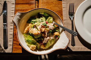 wooden table served with plates with salad and snacks, cutlery and glasses. 