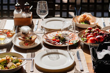 wooden table served with plates with salad and snacks on the open terrace