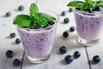 Fototapeta na wymiar Blueberry smoothie with milk and mint in a glass, on rustic wooden table.