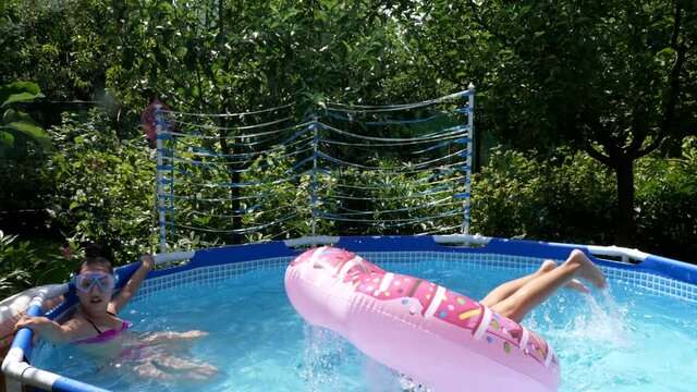Children in goggles enjoy chilling and diving through donut float in swimming pool in summer, dive