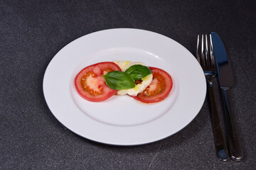 Tomato with Mozzarella and basil on a white porcelain plate