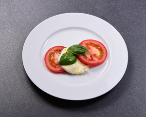 Tomato with Mozzarella and basil on a white porcelain plate
