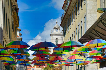 Fototapeta na wymiar Colored umbrellas between buildings in the pink street of Lisbon (Portugal)