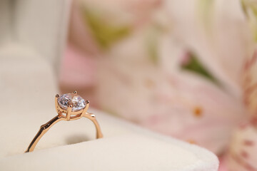 Beautiful engagement ring with gemstone in box on blurred background, closeup. Space for text
