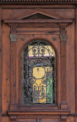 Details in ornate antique brown wooden door with mouldings of architectural elements and leaded...