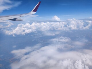 Wing of airplane flying above the clouds in the sky in India 