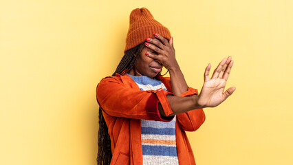 afro black pretty woman covering face with hand and putting other hand up front to stop camera,...