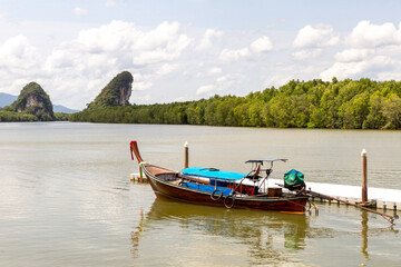 blue motor boat near the pier on the background of green mountains covered with jungle