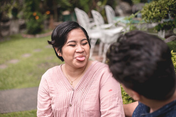 A filipino woman sticks out her tongue while having playful banter with her husband. A fun...