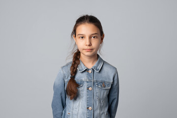 Portrait of smiling preteen girl looking at camera with happy facial expression, isolated on grey...