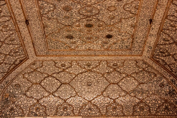 Ornate carvings and mirrorwork on the ceilings of the Sheesh Mahal palace in the Amer Fort in the city of Jaipur.