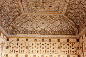Fototapeta na wymiar Ornate carvings and mirrorwork on the ceilings of the Sheesh Mahal palace in the Amer Fort in the city of Jaipur.