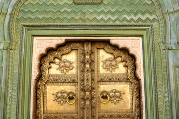 The beautiful metal door with ornately carved patterns on the wall at the ancient City Palace in...