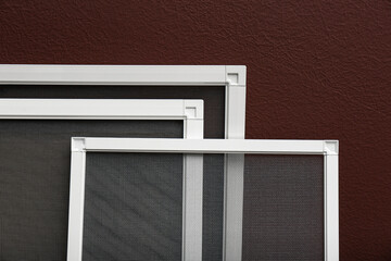 Set of window screens near brown wall, closeup