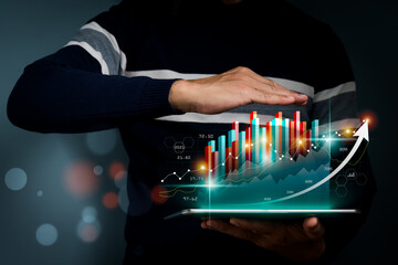 The concept is a business strategy, Abstract icon, Digital marketing. A businessman using tablet computer analyzing sales data and economic growth graph chart.