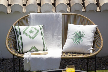 wicker sofa with two cushions and a white towel on a terrace