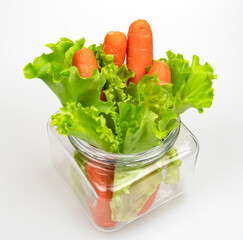Lettuce leaves and carrots in a glass transparent bottle on a light background. Top view