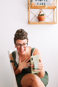 Cheerful woman using phone wearing a turbant at home