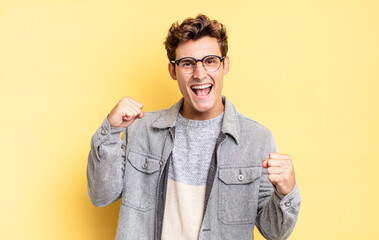 young teenager boy feeling happy, positive and successful, celebrating victory, achievements or...