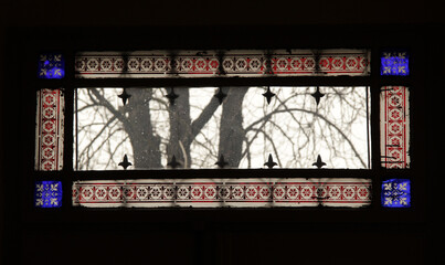 Dirty stained glass window overlooking leafless trees