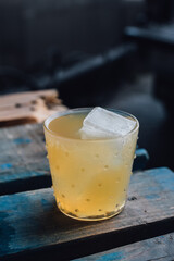 yellow coconut cocktail in rocks glass with ice on blue wood happy hour